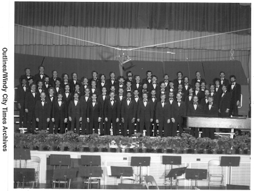 Photo of the original WCPA chorus. It is in black and white and the chorus members stand on a stage together.